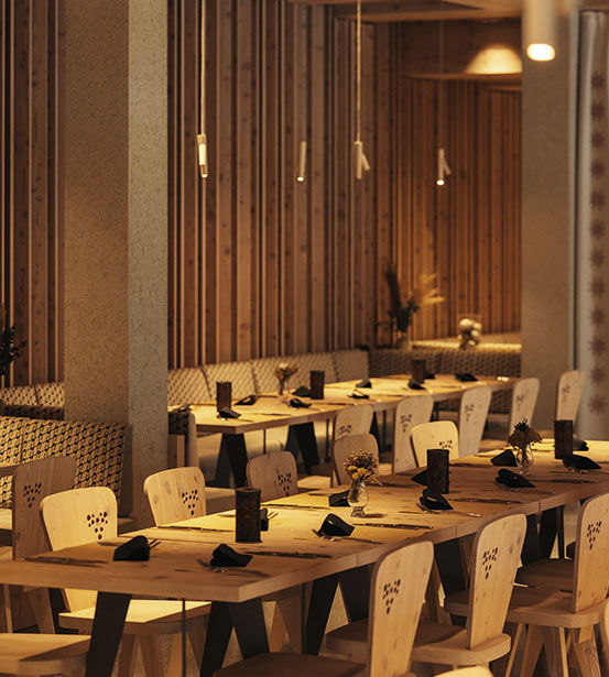 hotel bohinj Prijetna notranjost restavracije z lesenimi mizami in stoli, vzorčastimi klopmi, mehko visečo razsvetljavo in minimalističnim dekorjem. Na vsaki mizi so postavljene majhne vaze s cvetjem, ki ustvarjajo toplo in vabljivo vzdušje.